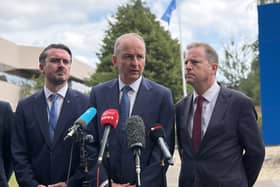 Micheál Martin, centre, in front of news microphones