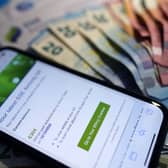 An energy bill displayed on a smartphone in front of banknotes