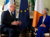 John Swinney and Catherine Connolly talking to each other, seated in front of Irish, Scottish and EU flags