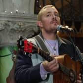 Dermot Kennedy holding a guitar and singing